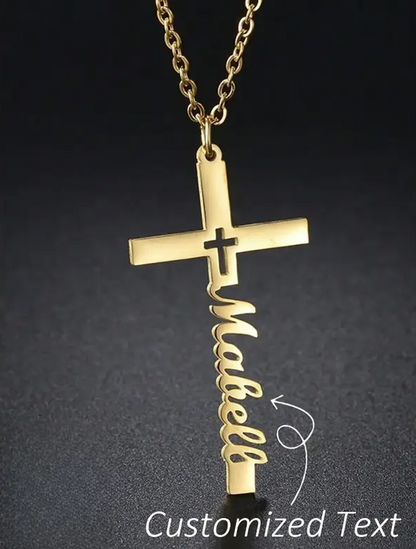Gold cross necklace with 'Mabell' text on a dark background. Arrow points to name and says "Customized text"