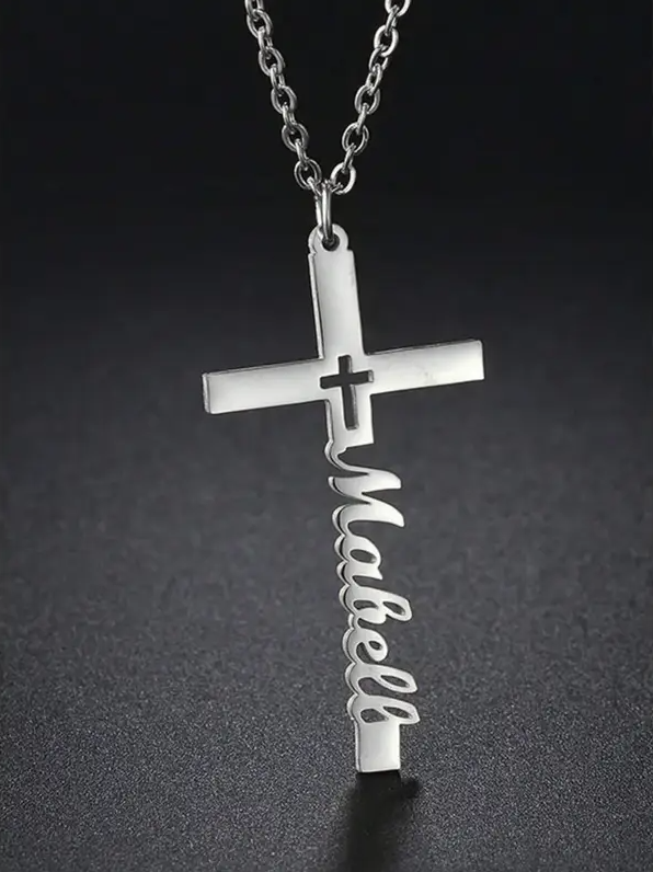 Silver cross necklace with 'Mabell' on a dark background